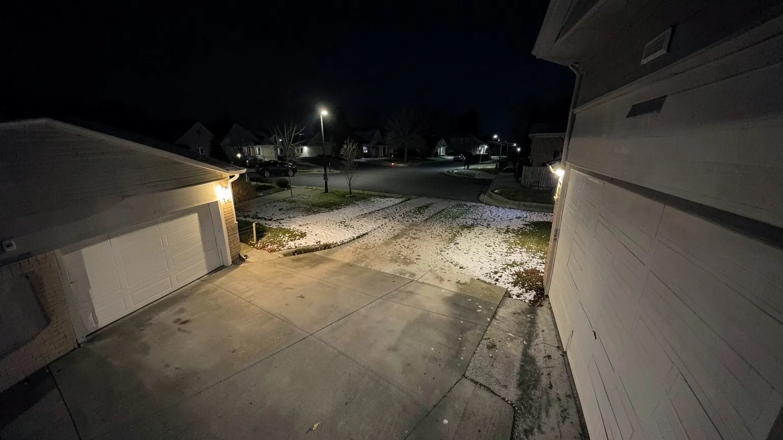 Camera view of a driveway and quiet street at night, in full colour